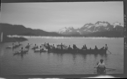 Image of 14 kayakers, many women in oomiak [umiak]